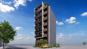 A modern multi-story building with balconies, surrounded by greenery and a clear sky. - Minn Asakusa Hanayashiki North (Tokyo)