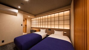 A hotel room with two beds, a desk, a chair, and a wall with a grid pattern. - Minn Asakusa Hanayashiki North (Tokyo)