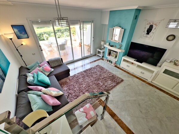 Ein modernes Wohnzimmer mit einer Couch, einem Fernseher und Blick ins Freie.
