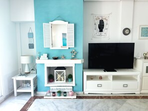 Ein Wohnzimmer mit einer Türkis-farbenen Akzentwand, einem Kamin, einem Fernseher und einem kleinen Tisch mit Dekoration.