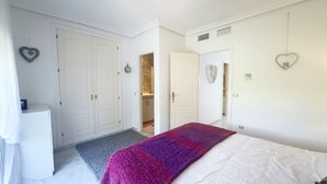 Ein Schlafzimmer mit einem Bett, einem Kleiderschrank, einer Tür zu einem Badezimmer und einem kleinen Tisch mit einer Lampe.