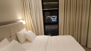 Ein Hotelzimmer mit einem großen Bett, einem Kopfteil und Vorhängen.
