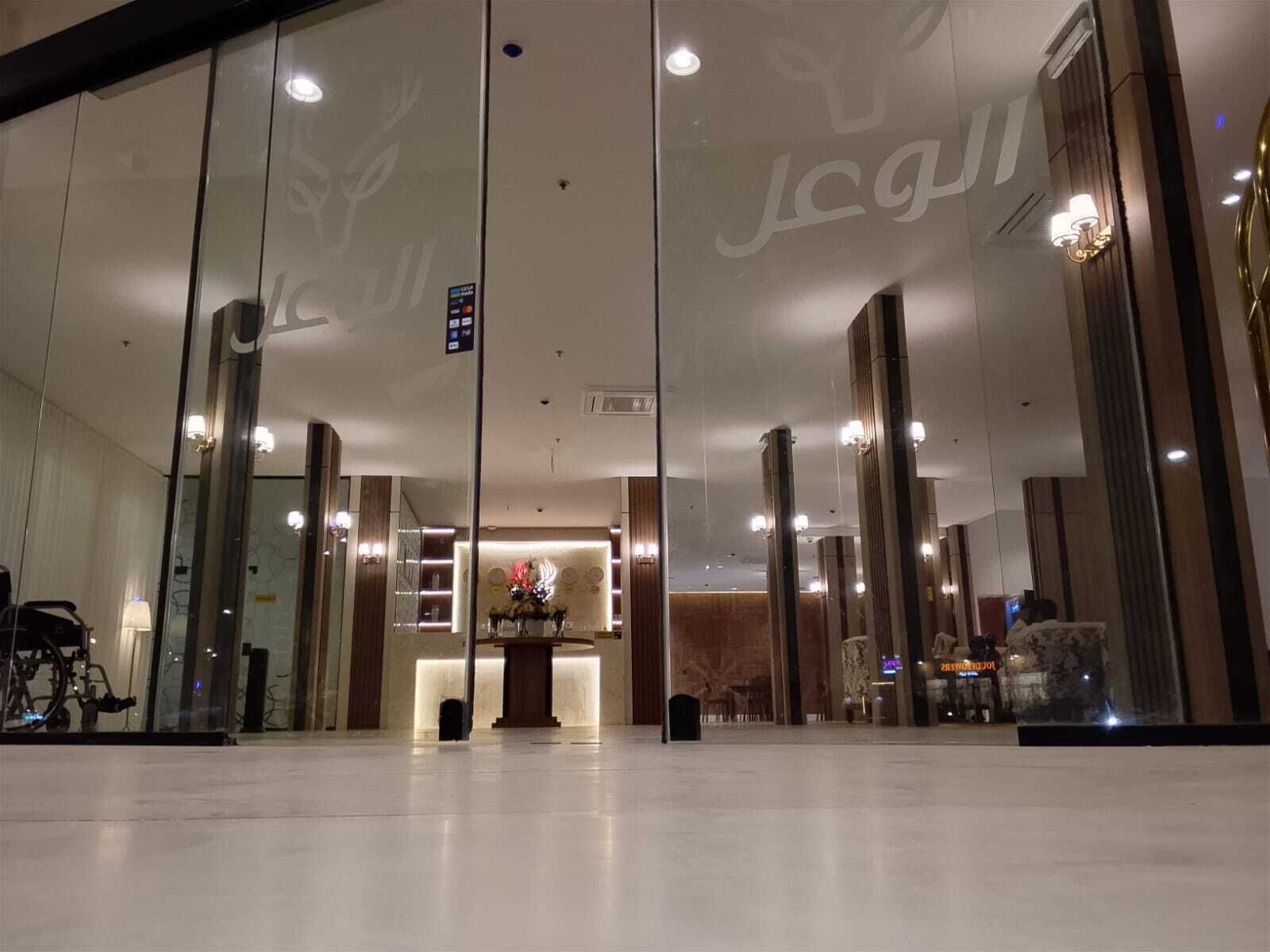 Un hall d’hôtel avec un comptoir d’accueil, un mur de verre et un reflet de l’intérieur.