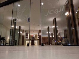 A hotel lobby with a reception desk, a glass wall, and a reflection of the interior.