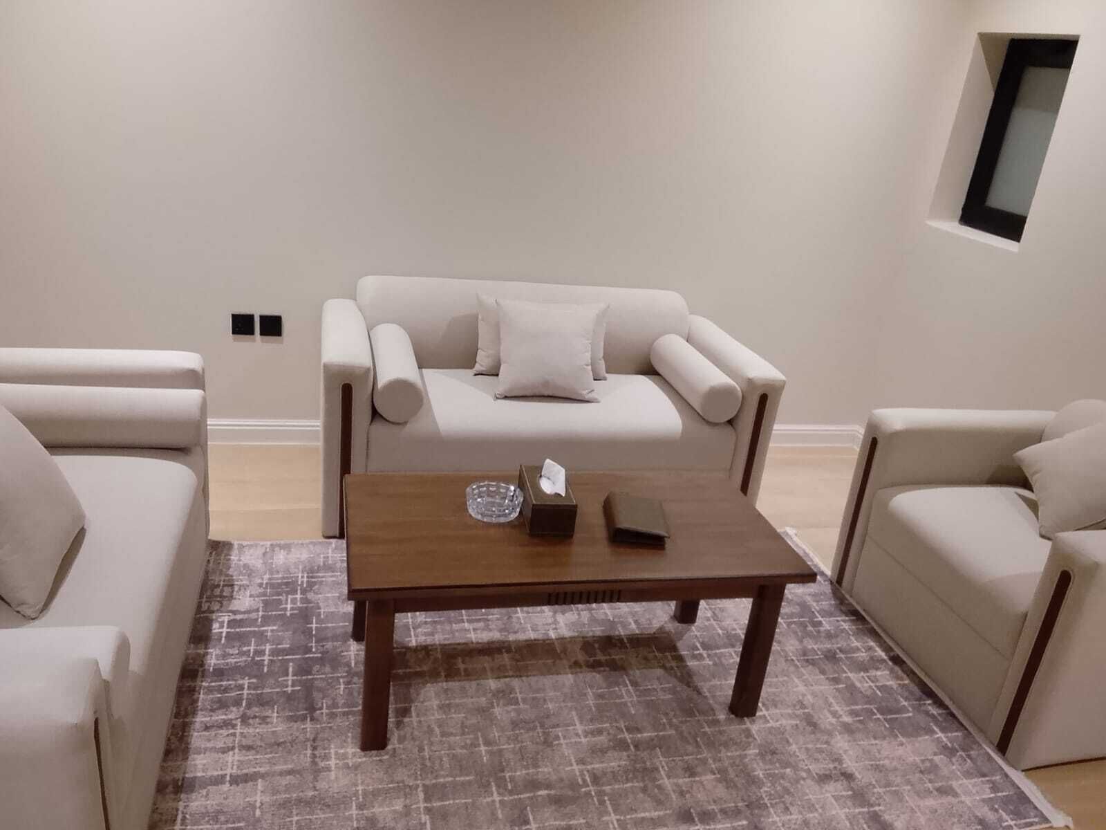 Una sala de estar con un sofá, dos sillones, una mesita de centro y un ventanal pequeño.