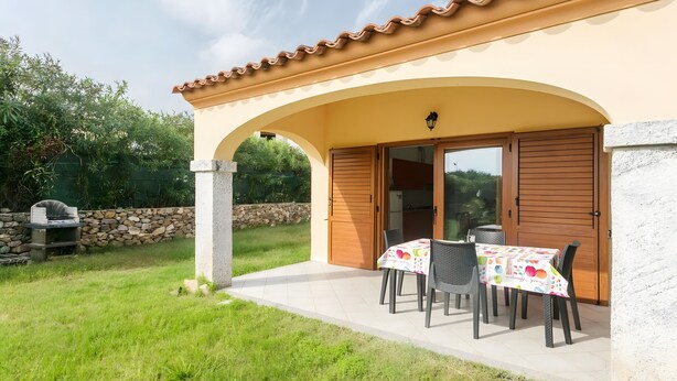 Un patio con una mesa y sillas, un muro de piedra y una puerta de madera.