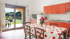 Una cocina con una mesa de comedor, sillas y vista al jardín a través de puertas de vidrio.