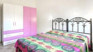 Un dormitorio con cama, armario y lámpara fijada a la pared.
