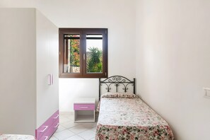 A bedroom with a bed, a window, a small desk, and a wardrobe. - Holiday Home 'Caposchiera Residence Marongiu' with Private Garden, Balcony and Air Conditioning (Porto Ottiolu)