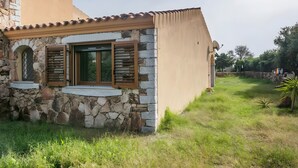 Una casa de piedra con tejado de baldosas, una ventana con contraventanas y una antena parabólica.