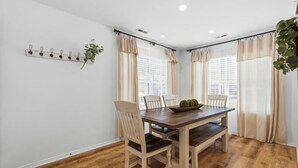 A dining area with a wooden table, four chairs, a plant, and a wall-mounted light fixture. - Lakefront walk-in condo overlooking Marina (Branson)