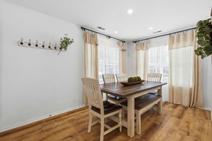 A dining area with a wooden table, four chairs, a plant, and a wall-mounted light fixture. - Lakefront walk-in condo overlooking Marina (Branson)