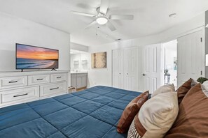 A bedroom with a large bed, a ceiling fan, a TV, a bathroom, and a door leading to another room. - Lakefront walk-in condo overlooking Marina (Branson)