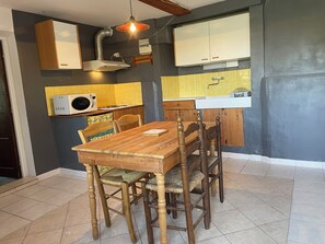 A kitchen with a wooden table and chairs, a microwave, a sink, and cabinets. - Lovely 2-bedroom apartment in enchanting Saint-Sauveur awaits you (Saint-Sauveur)