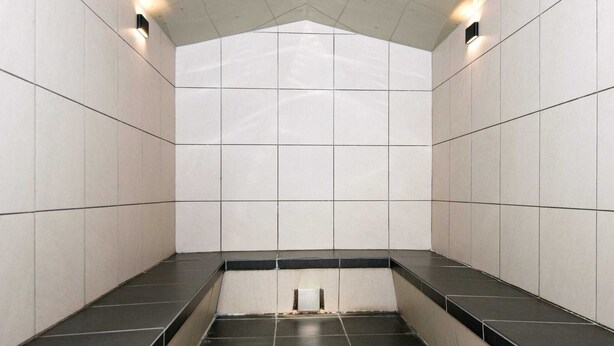 Une salle de bain carrelée avec des carreaux noirs et blancs, un sol noir et un plafond blanc doté d’un éclairage encastré.