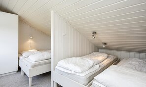 Un alojamiento pequeño y de una sola habitación con dos camas, techo inclinado e iluminación tenue.