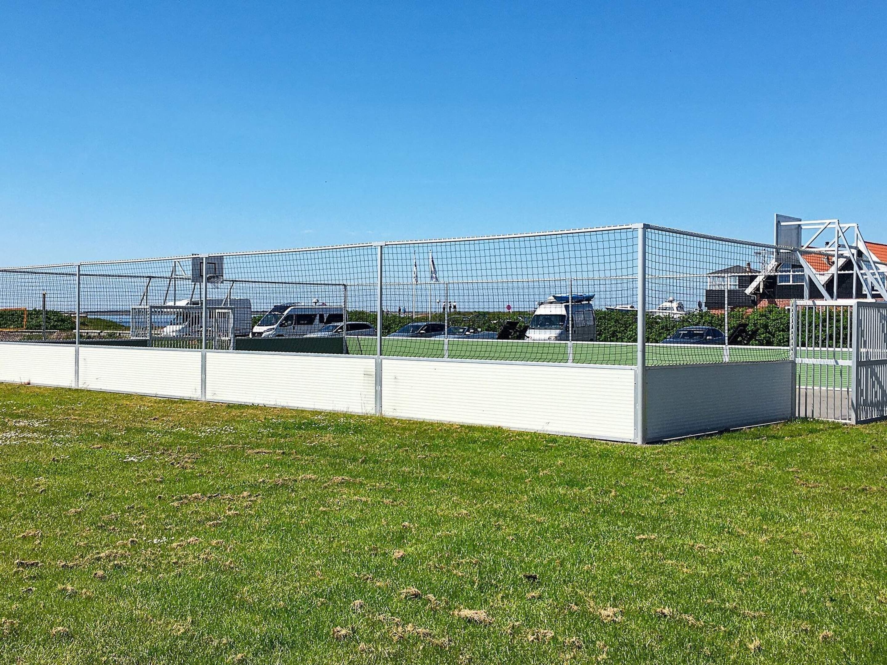 A fenced sports field with a white building in the background.