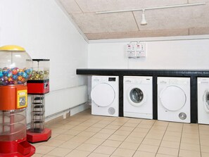 Pesuhuone, jossa on kolme pesukonetta, myyntiautomaatti ja kattovalaisin.