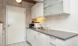 A modern kitchen with white cabinetry, a granite countertop, a coffee maker, and a microwave.