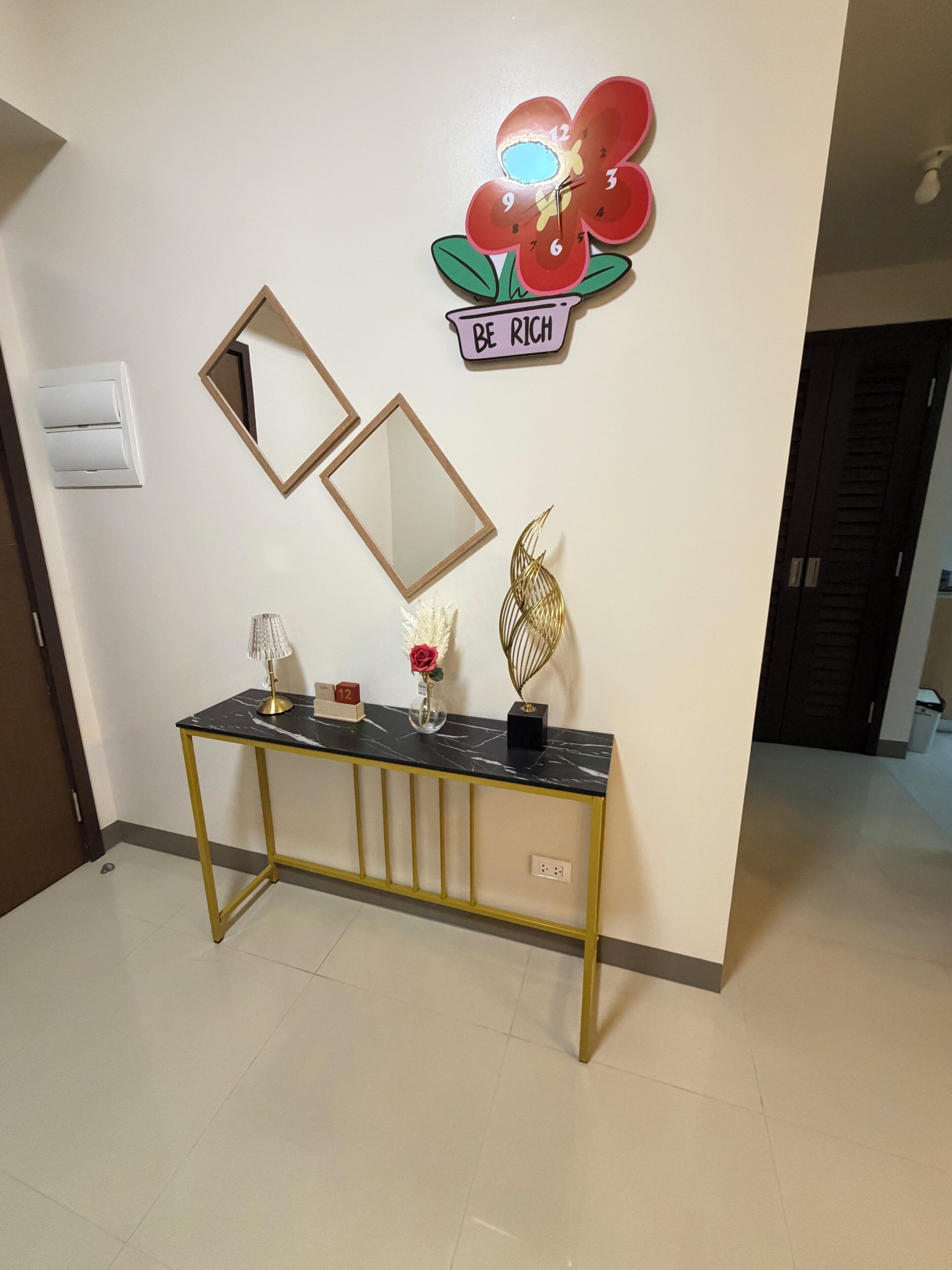 A hallway with a console table, a mirror, a clock, and a motivational poster.