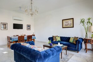 Ein Wohnzimmer mit einem blauen Sofa, einem Couchtisch und einem Essbereich mit Tisch für vier Personen.