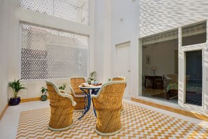 An indoor space with a patterned floor, wicker furniture, and a view through a glass door. - 2bhk suite in a bungalow (Jaipur)