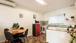 A compact kitchen with a dining area, a refrigerator, an oven, and a microwave.