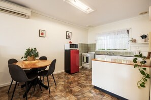 Una cuina compacta amb zona de menjador, nevera, forn i microones.