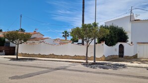 Un edifici blanc amb teulada de rajola, base de pedra i un petit arbre a la façana.