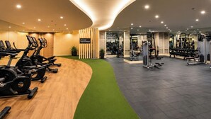 Ett modernt gym med konditionsmaskiner, styrketräningsmaskiner och ett område med grönt golv.
