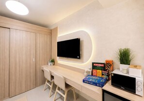 A modern kitchen with a flat-screen TV, a microwave, and a counter with board games. - Cozy Pool View 1BR Near MOA • Netflix (Pasay City)