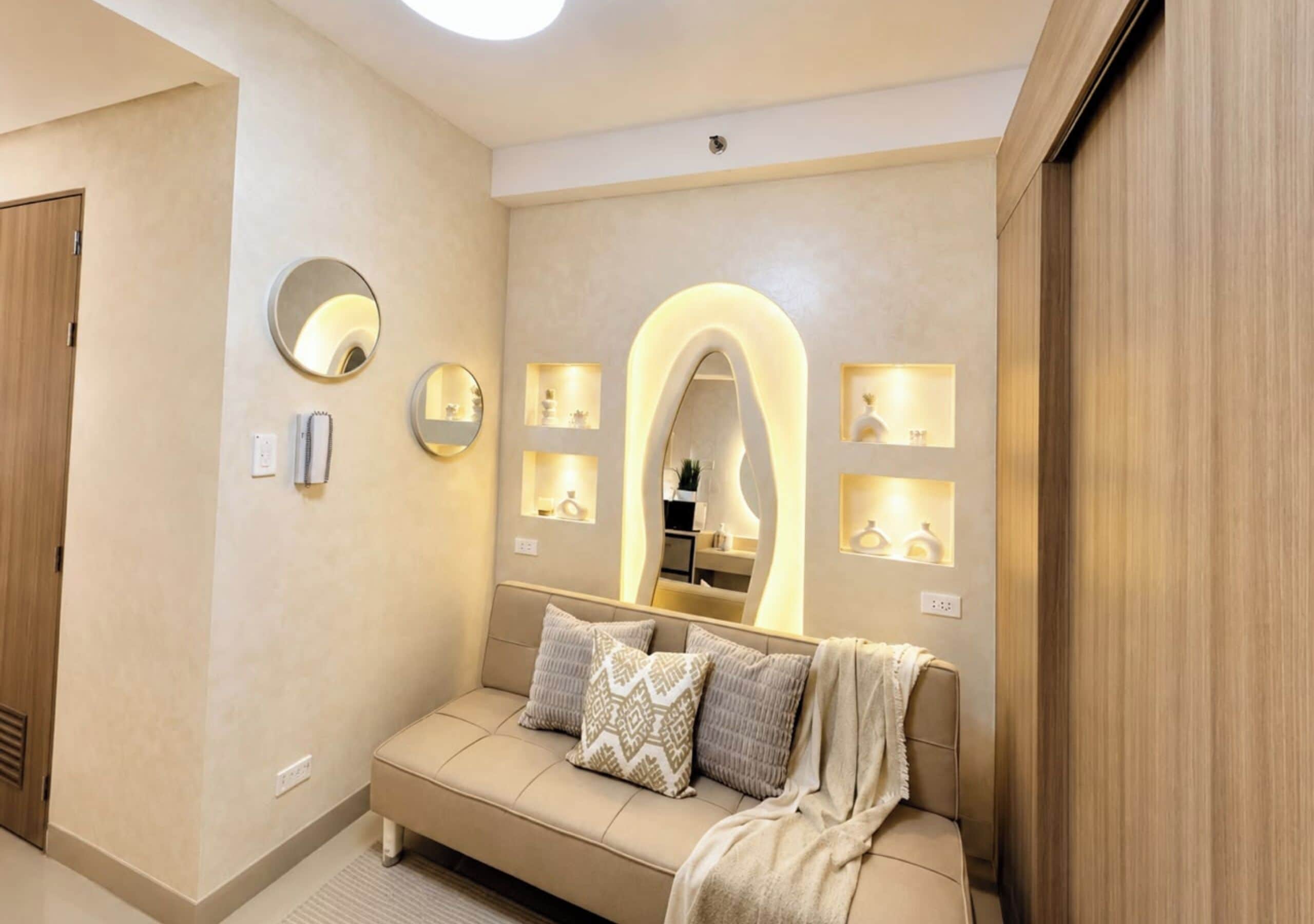 Ein modernes Hotelzimmer mit einer Couch, Spiegeln und Regalen an der Wand.
