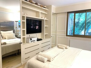 A hotel room with a bed, a television, a desk with a printer, and a window with a view of palm trees. - Elegance, comfort, and a sweeping view (Villefranche-sur-Mer)