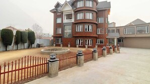 A multi-story building with a curved facade, multiple windows, and a gated entrance. - Palette Hotel Cecil Srinagar (Srinagar)