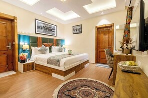 A bedroom with a bed, bedside tables, a desk, a chair, a television, and a window with skylights. - Palette Hotel Cecil Srinagar (Srinagar)