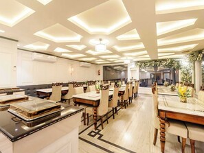 A spacious dining area with multiple tables and chairs, a central chandelier, and a decorative ceiling. - Palette Hotel Cecil Srinagar (Srinagar)