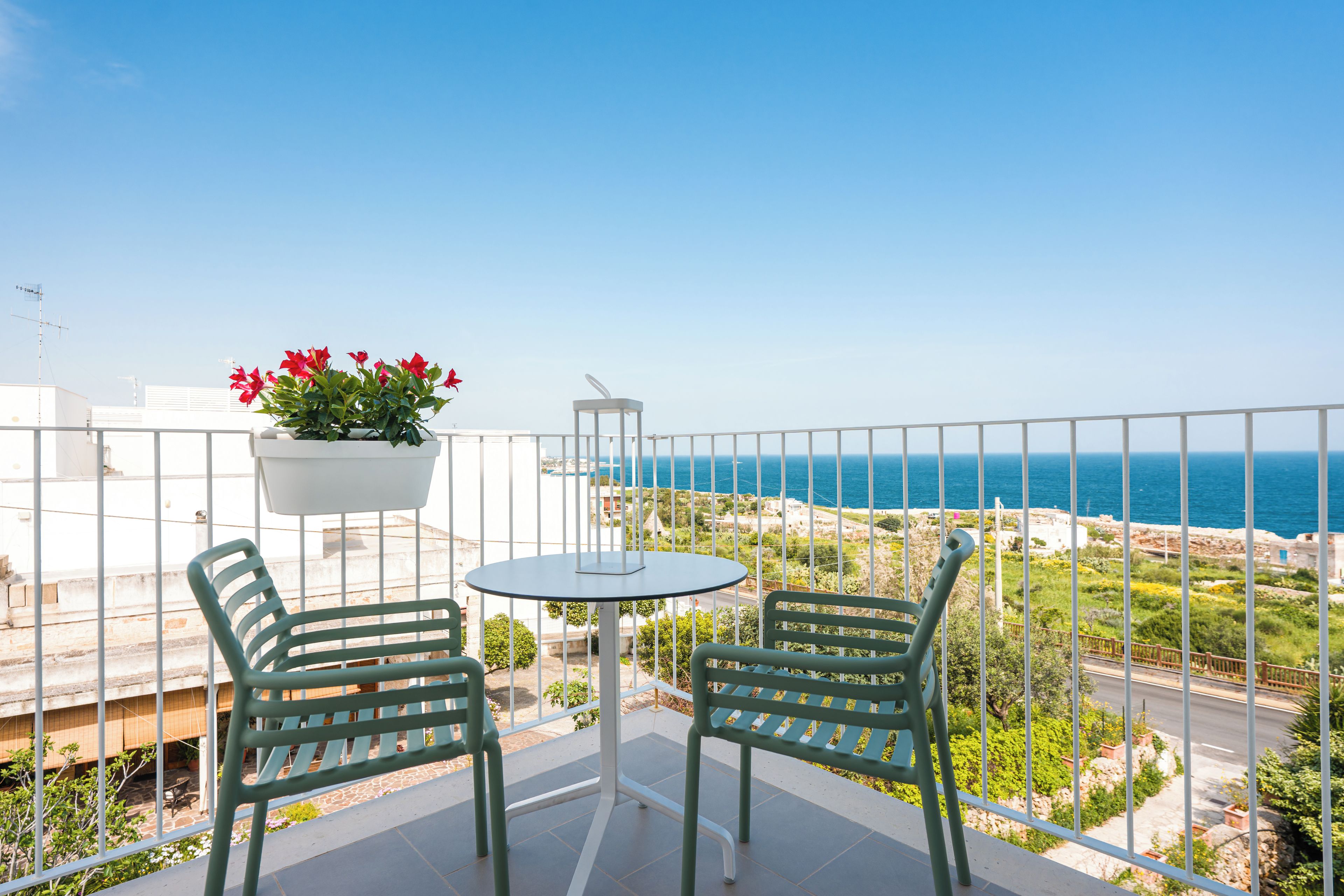 A balcony with two chairs and a table, overlooking a coastal view.
