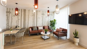A modern living room with a sofa, chairs, a coffee table, and a TV.