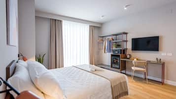 Habitación de hotel moderna con una cama grande, un escritorio con silla, un televisor y un armario.