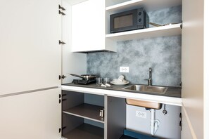 Una cucina compatta con microonde, fornelli, lavello e pensili.