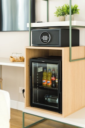 A compact refrigerator with a digital lock, containing beverages and a glass container.