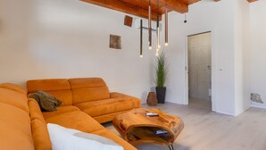 Ein modernes Wohnzimmer mit einer Eckcouch, einem Holztisch und einer Topfpflanze.