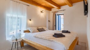 A bedroom with a wooden bed, a small table, and a window with sheer curtains. - Sarini dvori by Villas Guide (Svetvincenat)