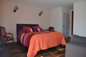 Un dormitori amb un llit, dues làmpades murals, una cadira i una porta.