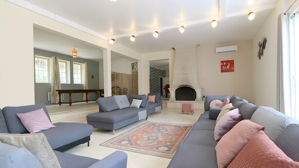 A living room with a large grey sofa, a patterned rug, and a fireplace. - Villa 'Alhambra' with Private Terrace, Wi-Fi and Air Conditioning (Vierzon)