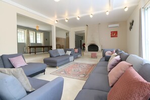 Un salon avec un grand canapé gris, un tapis à motifs et une cheminée.