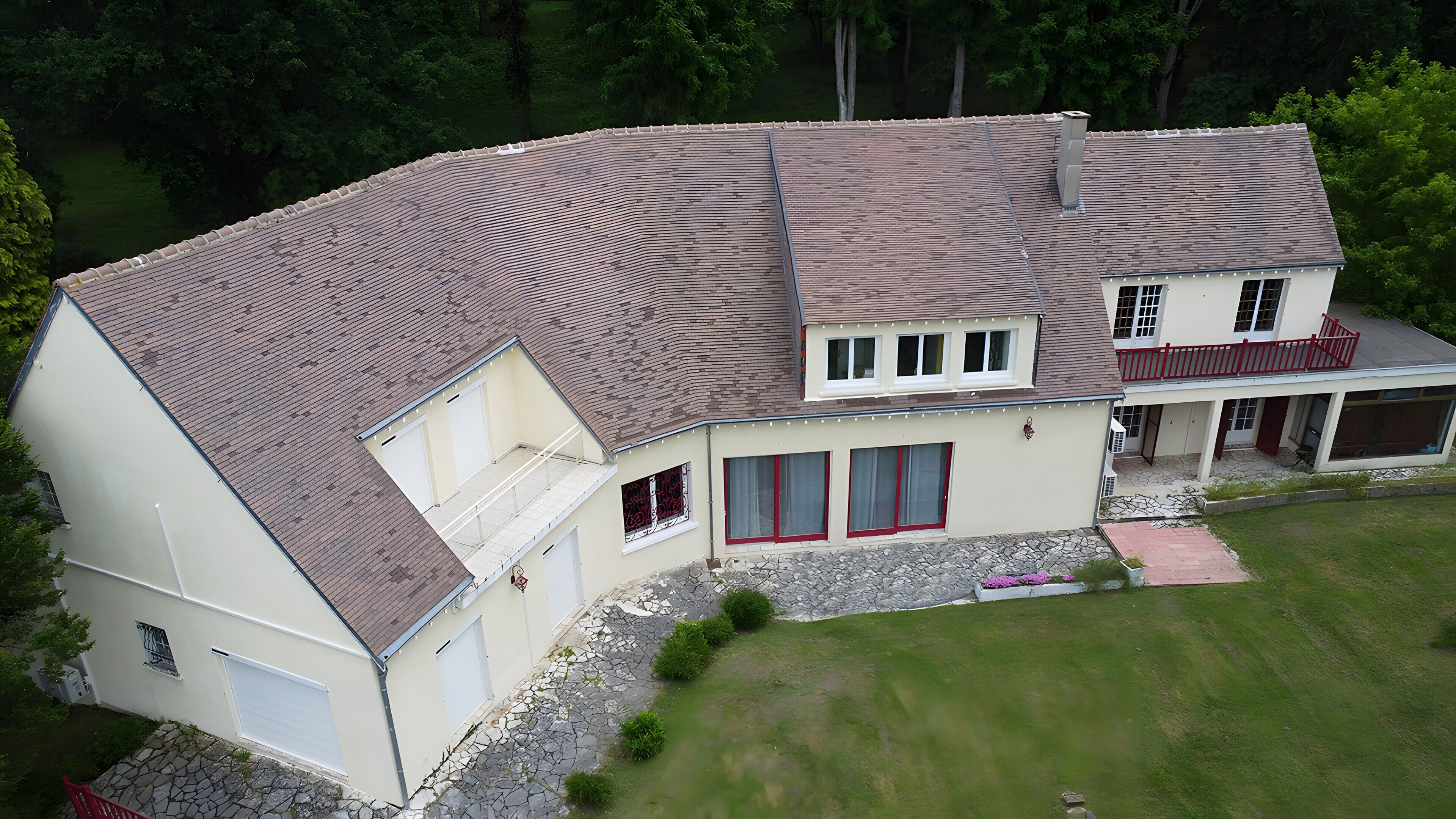 A two-story house with a sloped roof, a stone foundation, and a covered porch.