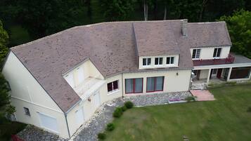 A two-story house with a sloped roof, a stone foundation, and a covered porch.