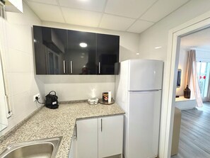 A compact kitchen with white cabinets, a built-in microwave, and a white refrigerator. - Oasis with panoramic views of the Mediterranean, a pool, and private parking (Peñiscola)