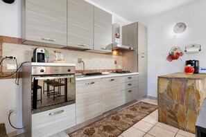 A modern kitchen with a built-in oven, a gas stove, and a coffee machine.